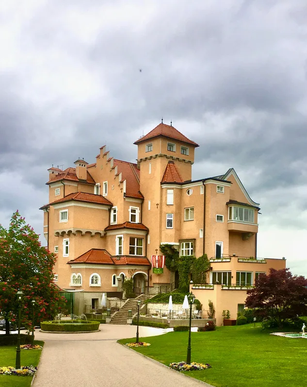 A turreted castle hotel above formal gardens under a grey sky.