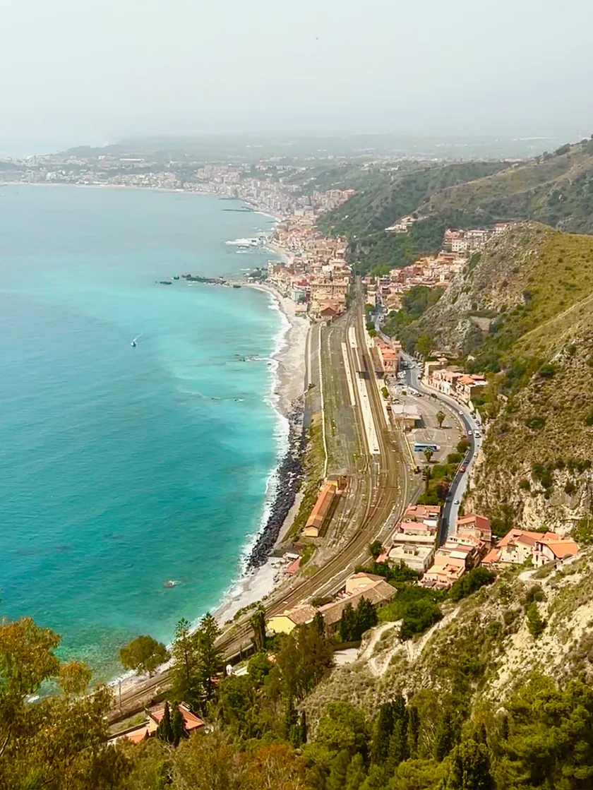 The view down from Taormina over the Ionian coast, turquoise sea meeting the hillside town below.